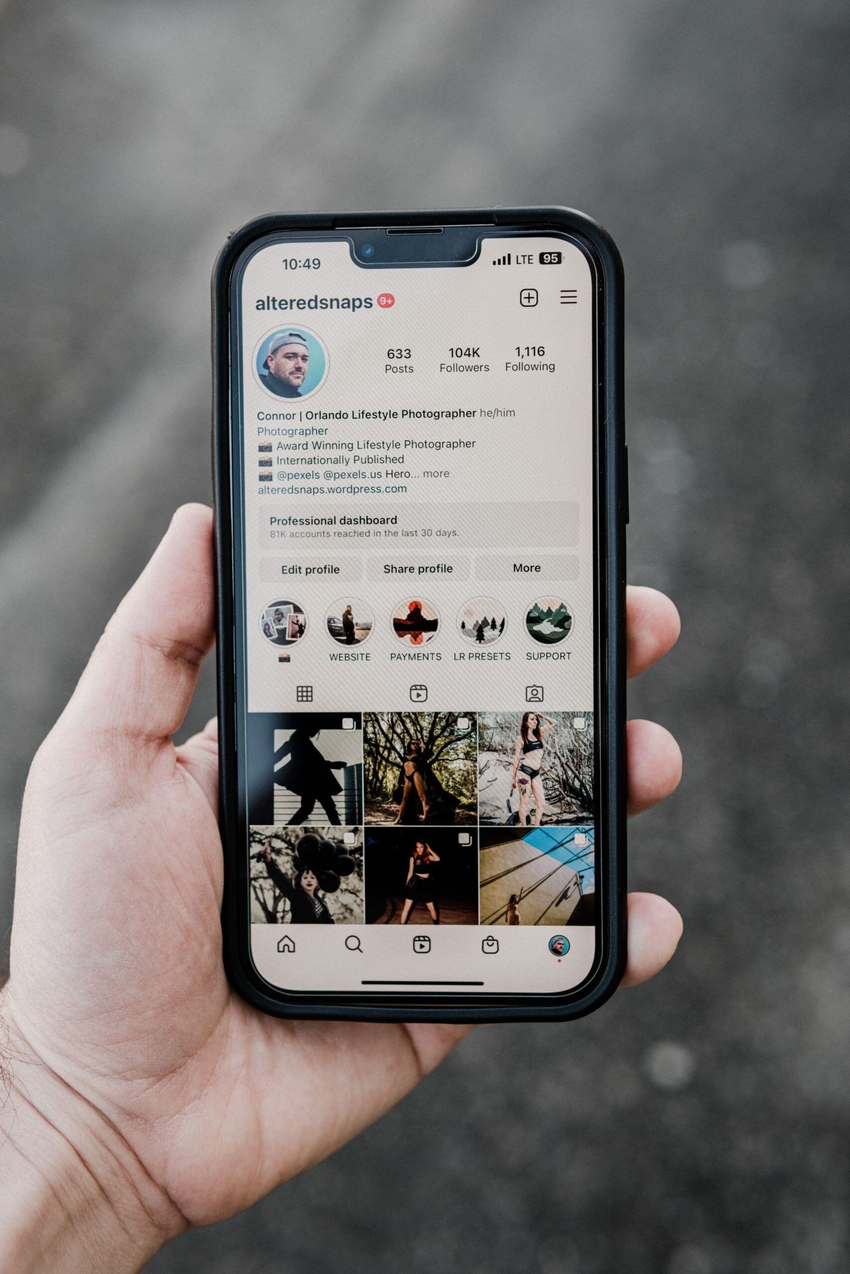 Close-up of hand holding smartphone showing Instagram profile on screen.